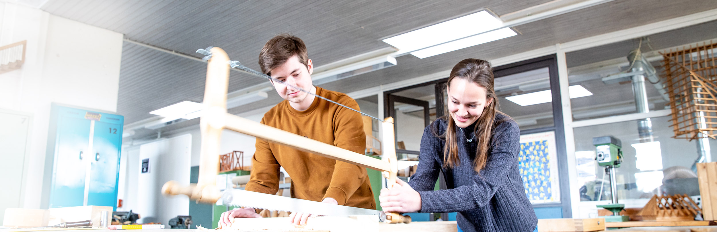 Schüler am sägen eines Holzstückes.