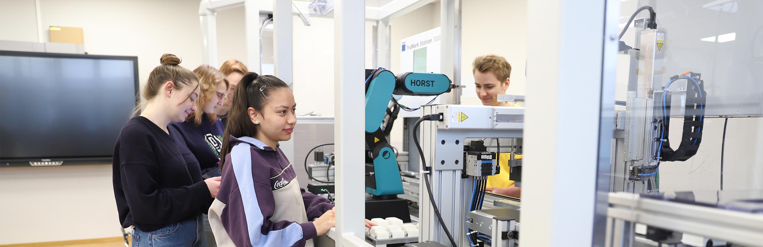 Schüler arbeiten an verkettetem Maschinensystem.